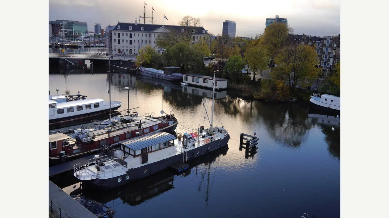Case galleggianti su un canale di Amsterdam con la luce dorata di inizio autunno