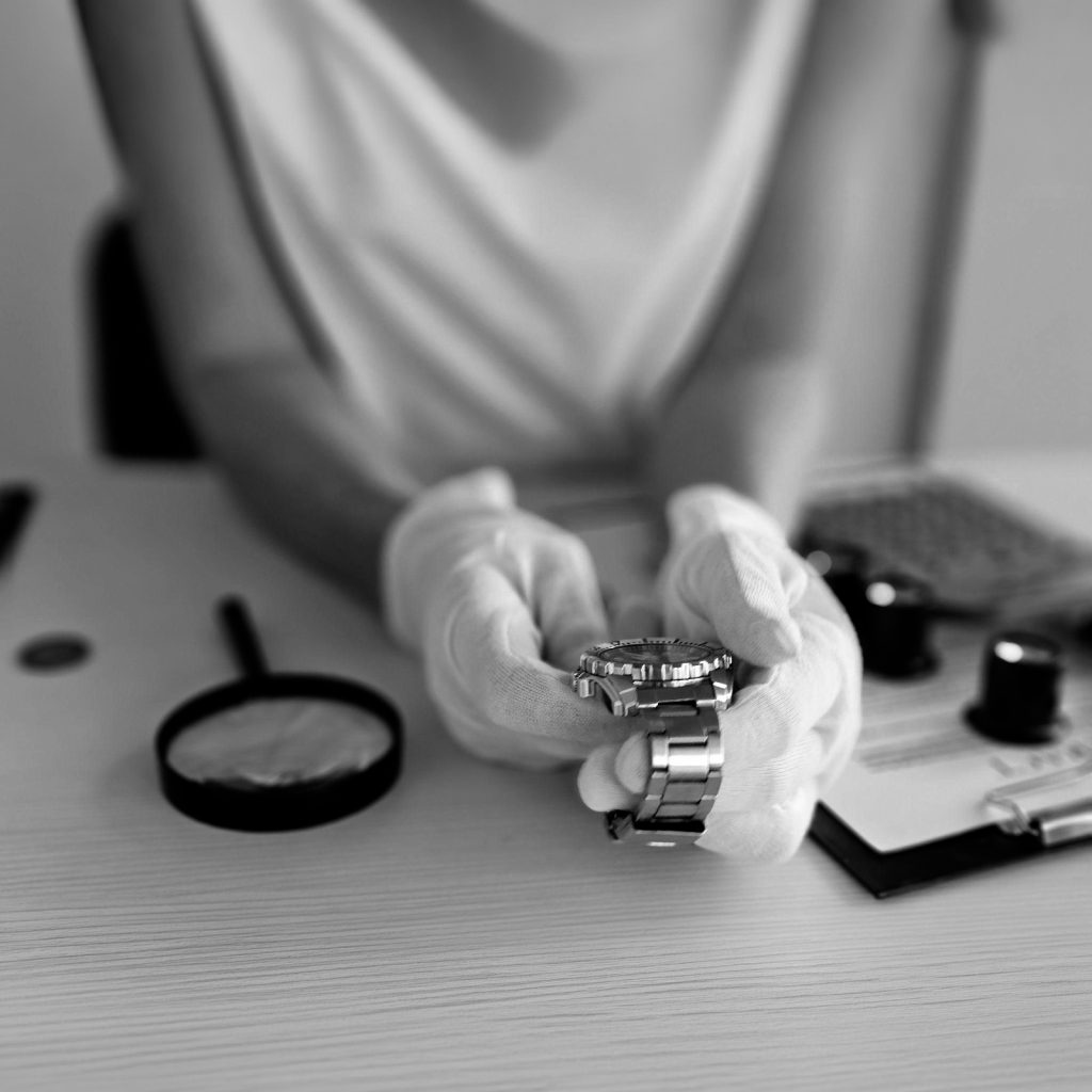 Professionista esperta con guanti bianchi esamina un orologio con lente d'ingrandimento, verifica autenticità beni Collecto